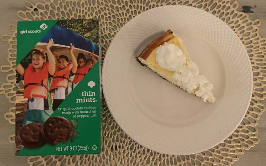A slice of thin mint cheesecake with a box of Girl Scouts thin mints