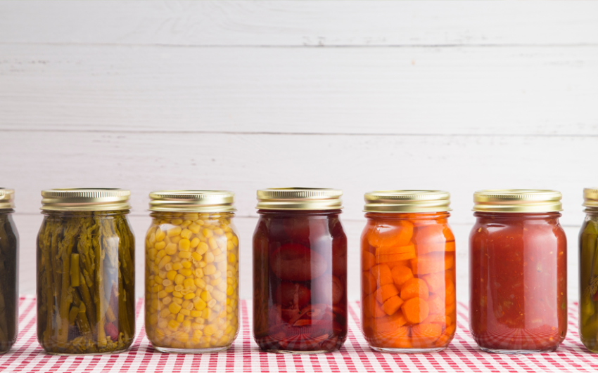 Various colorful vegetables in clear mason jars in a row.