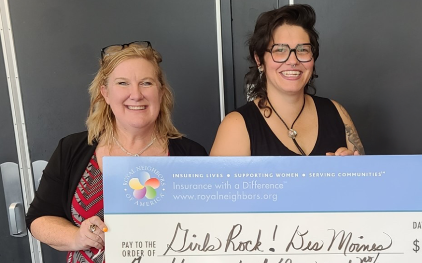 Two smiling women holding a giant check.