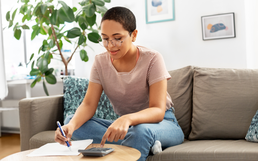 Woman sitting comfortably on her sofa while reviewing her finances.