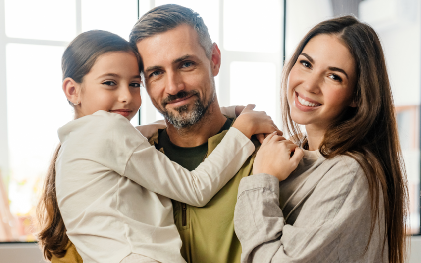 Father holding daughter on left and mother embracing father on the right. Happy, smiling family.