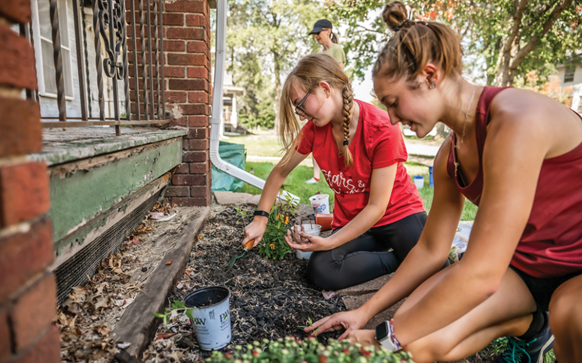 College students planting flowers for community members.