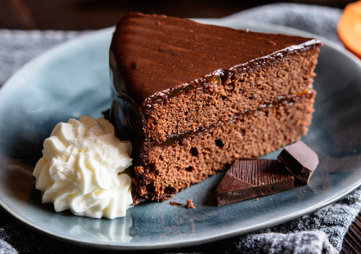 Close up photo of a piece of chocolate cake on a blue gray plate.