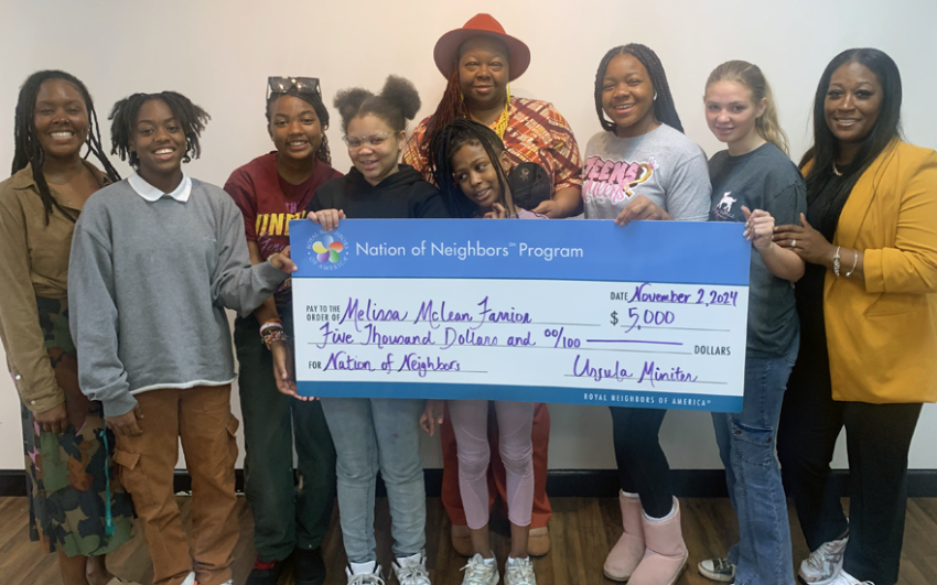 Group of happy young women and adults with a giant $5,000 Nation of Neighbors check.