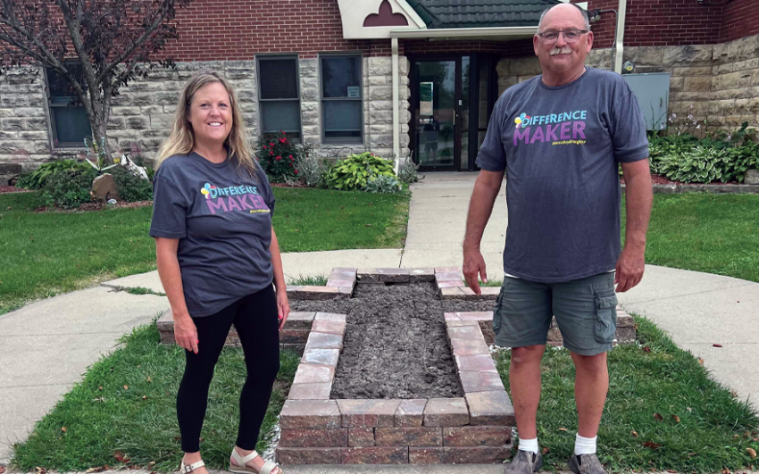 Two happy people outside of a church with gray Difference Maker t-shirts on.