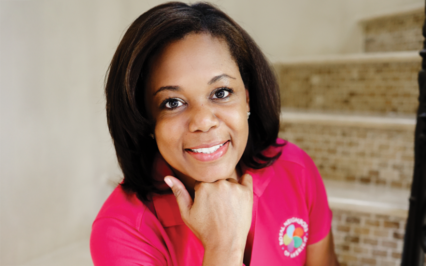 Smiling woman with pink Royal Neighbors of America polo shirt sitting on stairs.