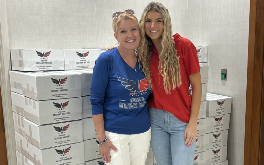 Smiling mother and daughter in front of several care packages for the military.