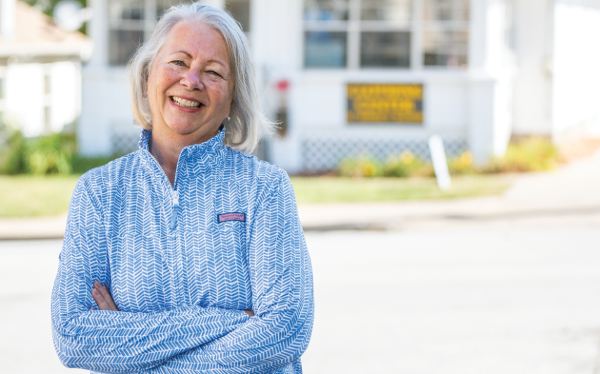 Smiling woman in light blue shirt in front of The Closing Center in the background.