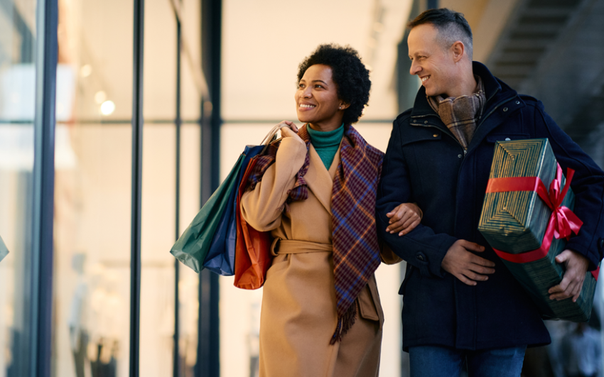 A happy couple hoping presents window shopping outside.