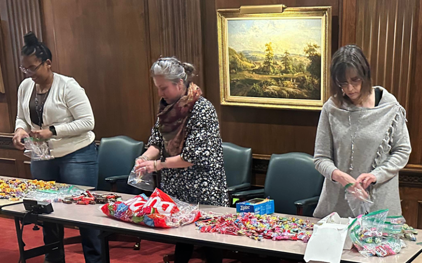 Three women assembling candy into plastic bags at a table.