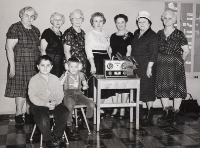 Black and with photo of a group of woman and children, one with headphones on. 